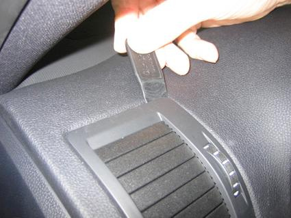 En hand håller en svart nyckel vid en ventil i en bil.