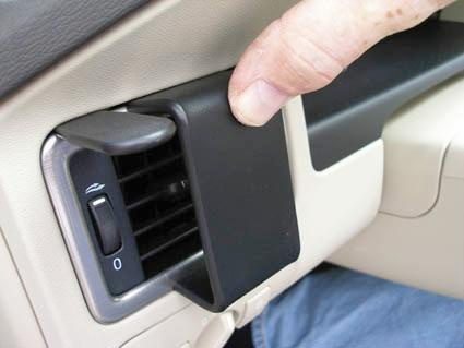 Knapplucka på bilens innersida, nära ventilreglage.