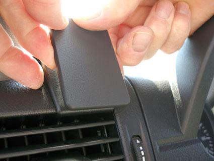 Hand som håller i en svart plastdetalj på en bilinteriör.