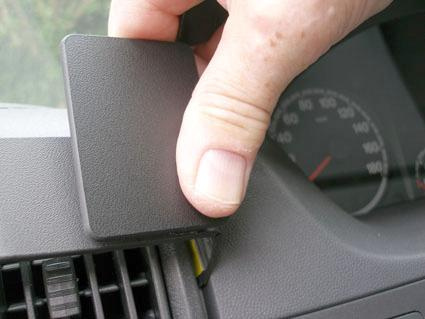 En hand håller i en svarts plastlucka på en bilinteriör.