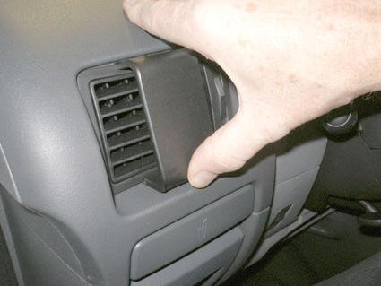 En hand som håller i en luftventil i en bilinteriör.