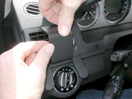 En person justerar en komponent i en Mercedes Benz C-Klass inredning.