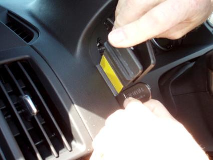 En hand placerar en enhet i en bils instrumentbräda.