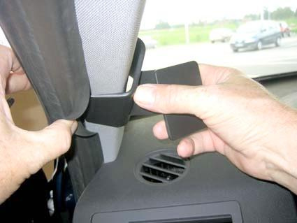 En hand fäster en del vid bilens vänstra högra sätesstolpe.