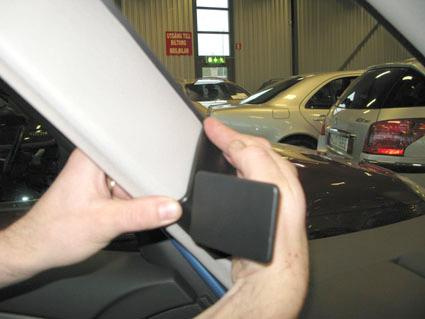 En hand som håller en del av bilens inredning vid ett fönster.