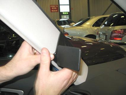 En person fäster ett sidofäste på en bils inredning.