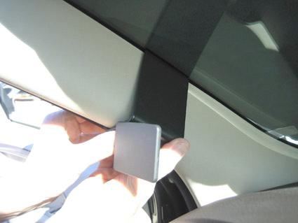 En hand håller i en svart fäste vid bilens tak.