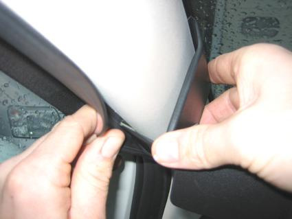 En person installerar en tätning på vänster sida av en Fiat 500.