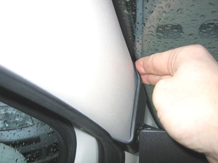 En hand justerar en tätningslist vid bilfönstret.