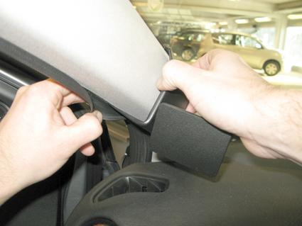 En manlig hand som demonterar en del av fordonets interiör.
