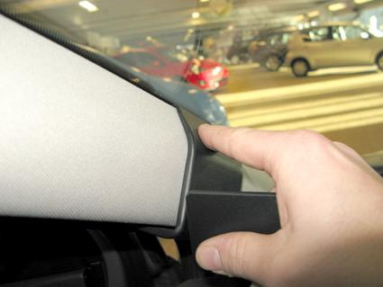 En hand som pekar på en del av bilens interiör.