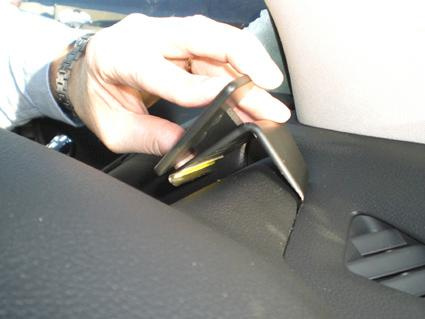 En hand placerar ett objekt i en inredningsdel av en bil.