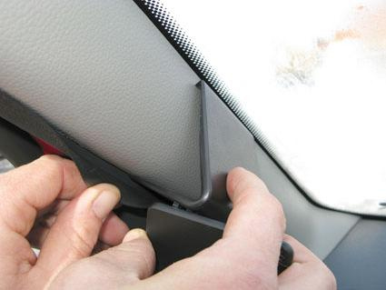 En hand som justerar inredning på vänstra sidan av Dacia Logan 07-08.