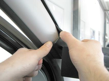 En hand som lyfter på en gummilist i en bil.