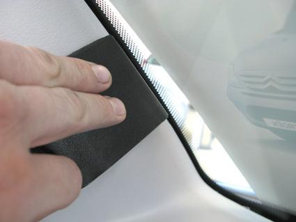 En hand placerad på en svart monteringsbygel vid fönsterrutan.