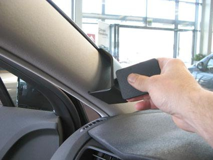 En hand placerar något på insidan av en bils vindruta.