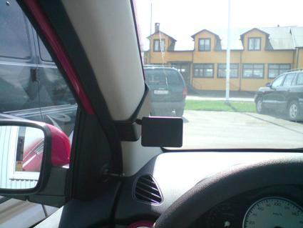 Sikt från insidan av en bil mot parkerade bilar och en byggnad.