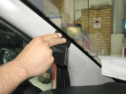 En hand som justerar en komponent vid vindrutans hörn i en Citroen Berlingo.