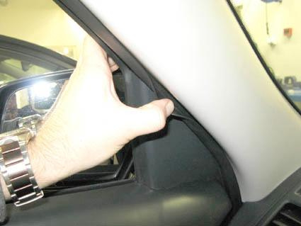 En hand justerar panelen vid vindrutan i Kia Soul 09-13.