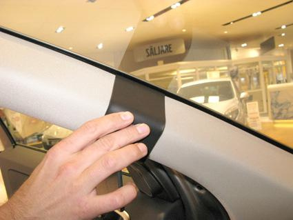 En hand placerad på en svart dekorrand i en bil interiör.