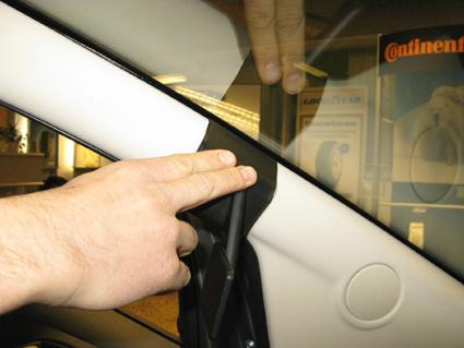 En hand som justerar eller installerar en komponent på vänster sida av en Ford Ka 09-15.