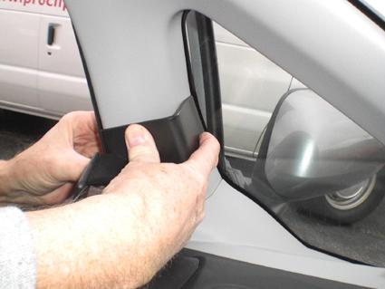 En person installerar en del på förarsidan av en Honda Fit/Jazz.