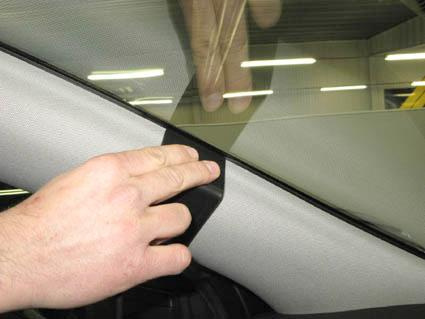 En hand trycker på en svart trimdel vid vindrutan på en Opel Insignia.