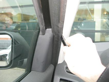 En hand som justerar eller rengör bilens interiör, nära vindrutan.