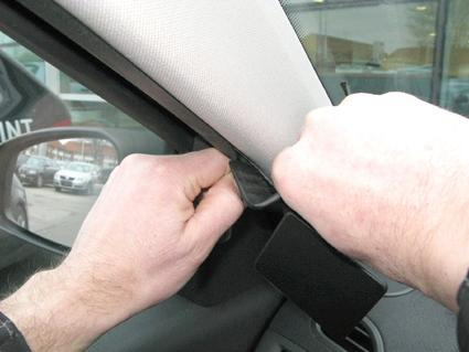 En person justerar eller tar bort en del från insidan av en bil.