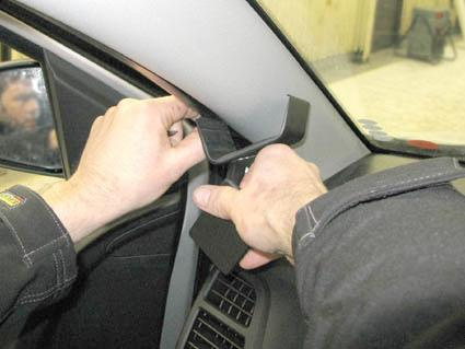 Två händer justerar något vid bilens vänstra sida, nära fönstret.