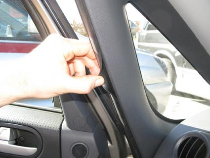 En hand som justerar en monteringsbygel i en bils dörr.