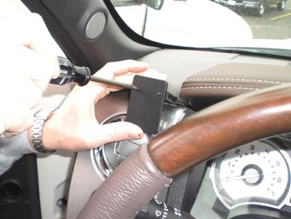 En hand skruvar fast en komponent i en Ford F-Series 150.