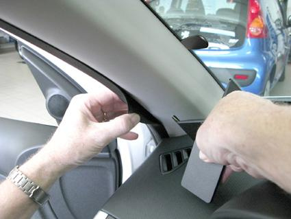 En hand som justerar en panel i en bilinteriör.