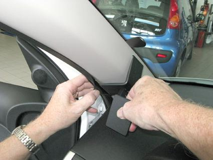 Hand som fäster en komponent på bilen Peugeot 206+ inuti kupén.