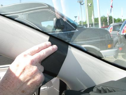 En hand som pekar på en del av bilens interiör.