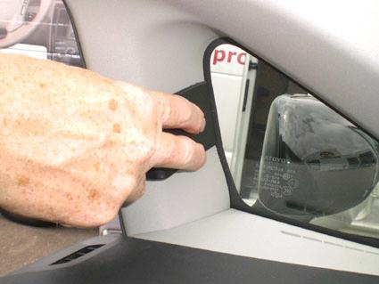 En hand som justerar något vid bilens fönsterkant.