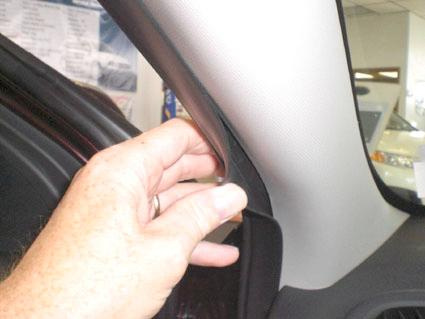 En hand som justerar en del av interiören i en Kia Cerato.