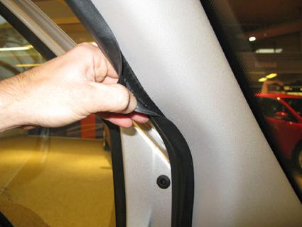 En hand håller i en tätning vid en dörrkarm på en Ford Transit Connect.