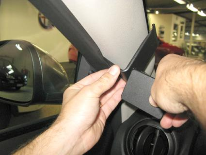 En hand som justerar en del vid bilens A-stolpe.