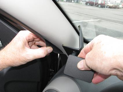 Bild visar en hand som installerar en del i en bil; troligen en bilinteriör.