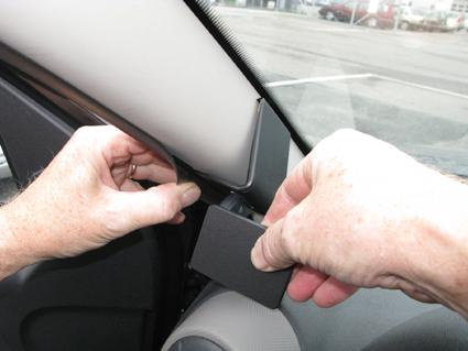 En hand installerar en svart del vid bilens inre hörn.