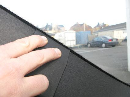 En hand trycker på en inre panel i en bil.