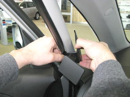 Händer monterar en bygel på bilens vänstra sida.