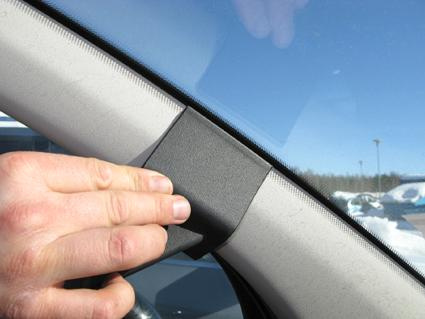 En hand fäster en svart panel vid vindrutan på en Citroen C3.