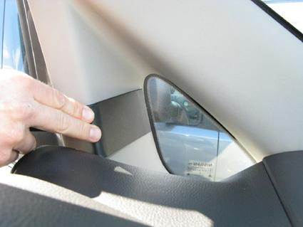 En hand pekar på en del av en bilinteriör, troligen en del av Nissan NV200.