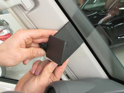 En hand håller en svart del som fästs vid bilens insida.