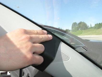 En hand placerad på en svart plastdetalj i en bils interiör.