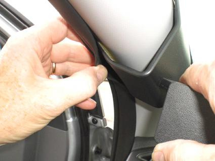 Händer som installerar en del på bilens inre struktur.