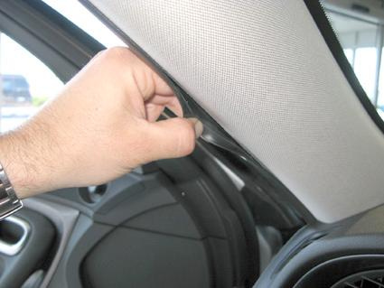 En hand som drar i en bils interiörpanel, troligtvis en Saab 9-5.