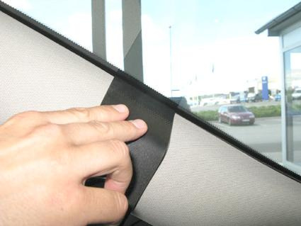 En hand justerar bilsätesklädseln vid fönstret.